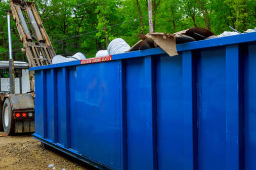 40 yard blue dumpster being dropped off by a dumpster transporter in Norwalk, CT.