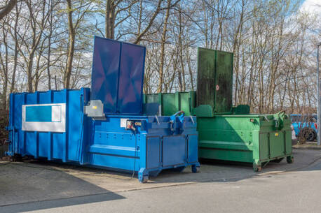 An open blue and green dumpster in a parking lot in Norwalk, CT.